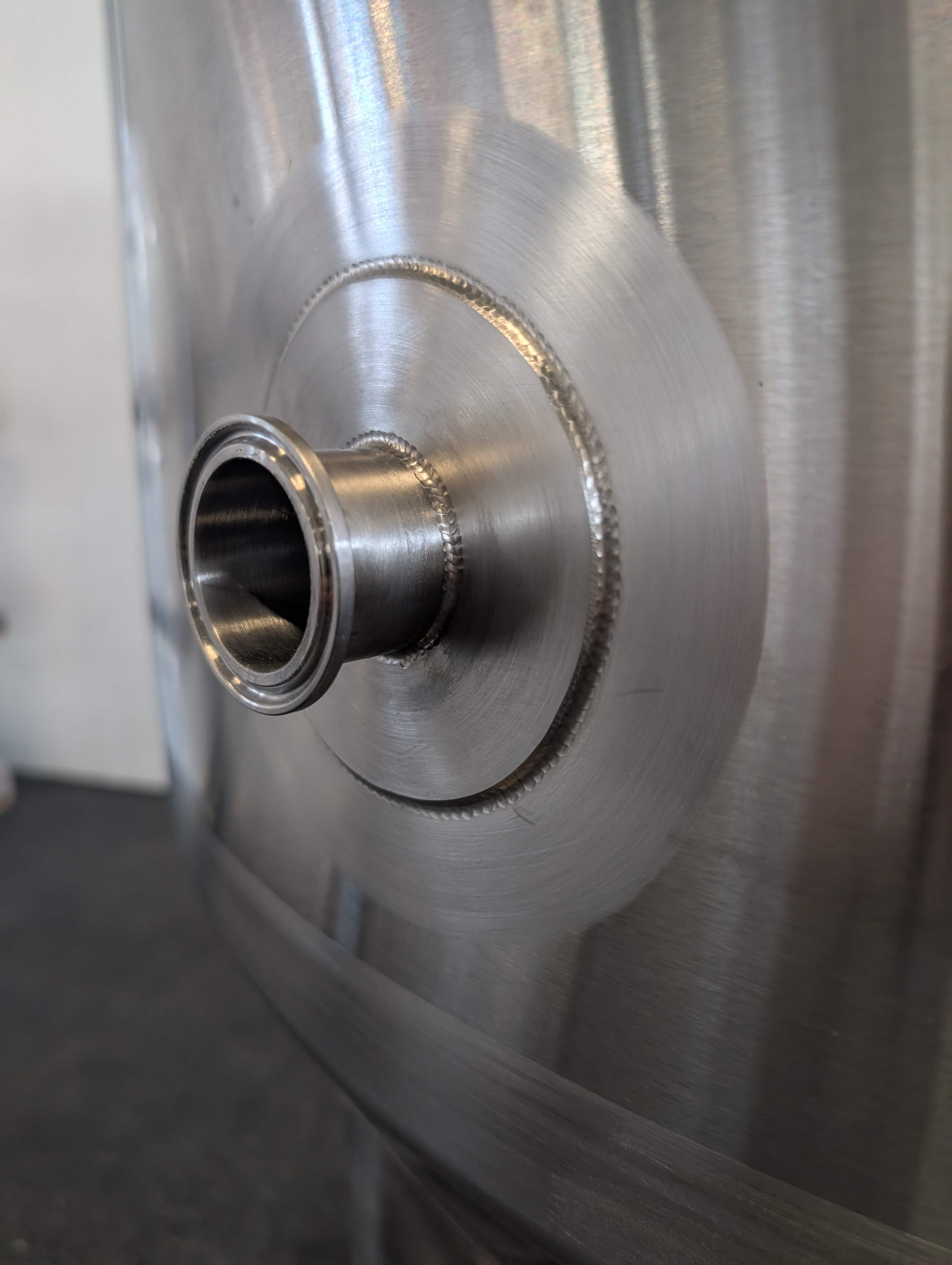Detailaufnahme der sauberen Schweißnähte an einem Tri-Clamp Anschluss des 500L Edelstahl Gärtanks.
